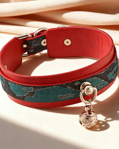 Christmas-style colla rmade of red leather and an outer layer of green patterned leather, featuring a gold bell in the center and a champagne-colored velvet background.