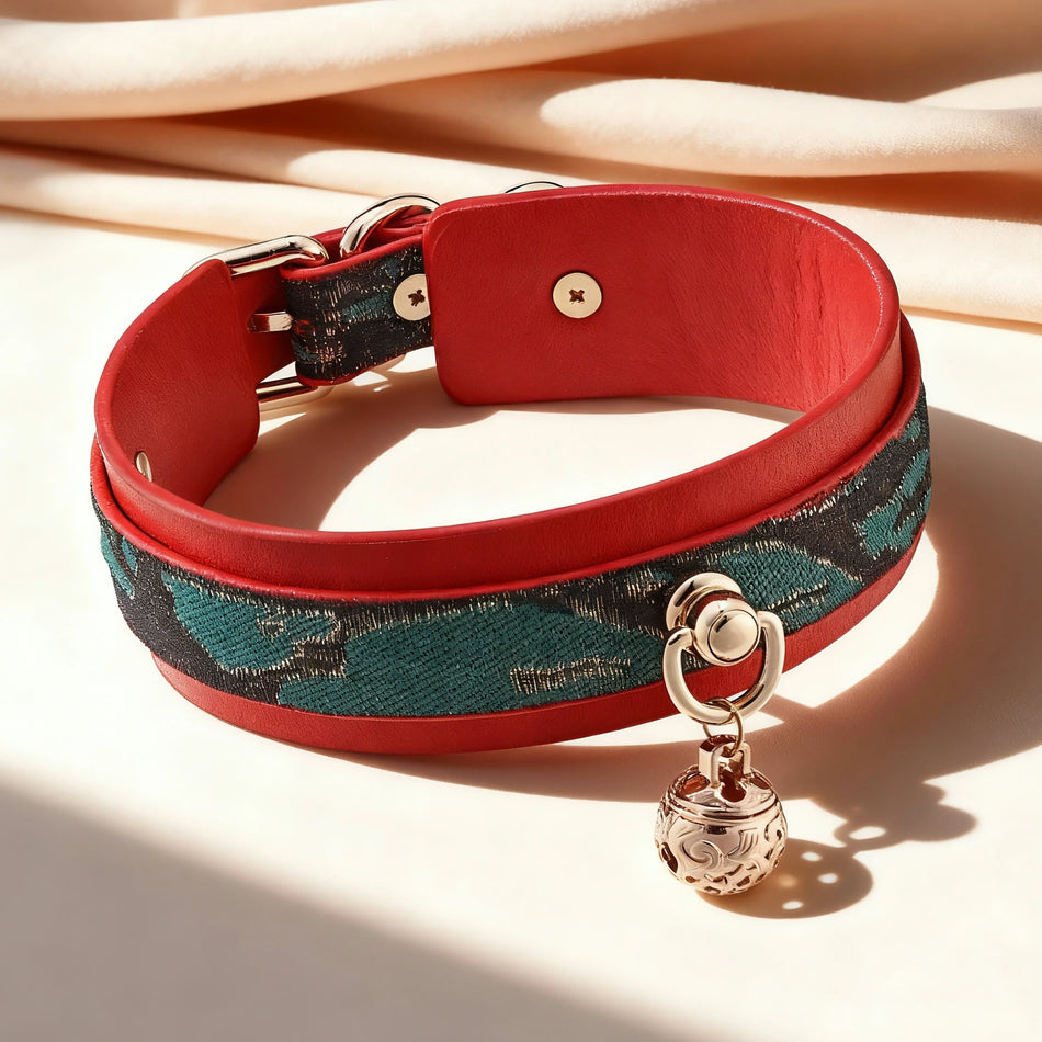 Christmas-style colla rmade of red leather and an outer layer of green patterned leather, featuring a gold bell in the center and a champagne-colored velvet background.
