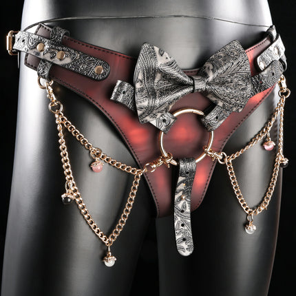 Red heat-reactive leather and black embossed leather strap-on harness with paisley embossed bow, featuring gold chains and colorful bead charms
