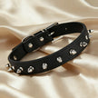 Black leather punk choker with silver metal cone spikes and an adjustable silver buckle on a silk background