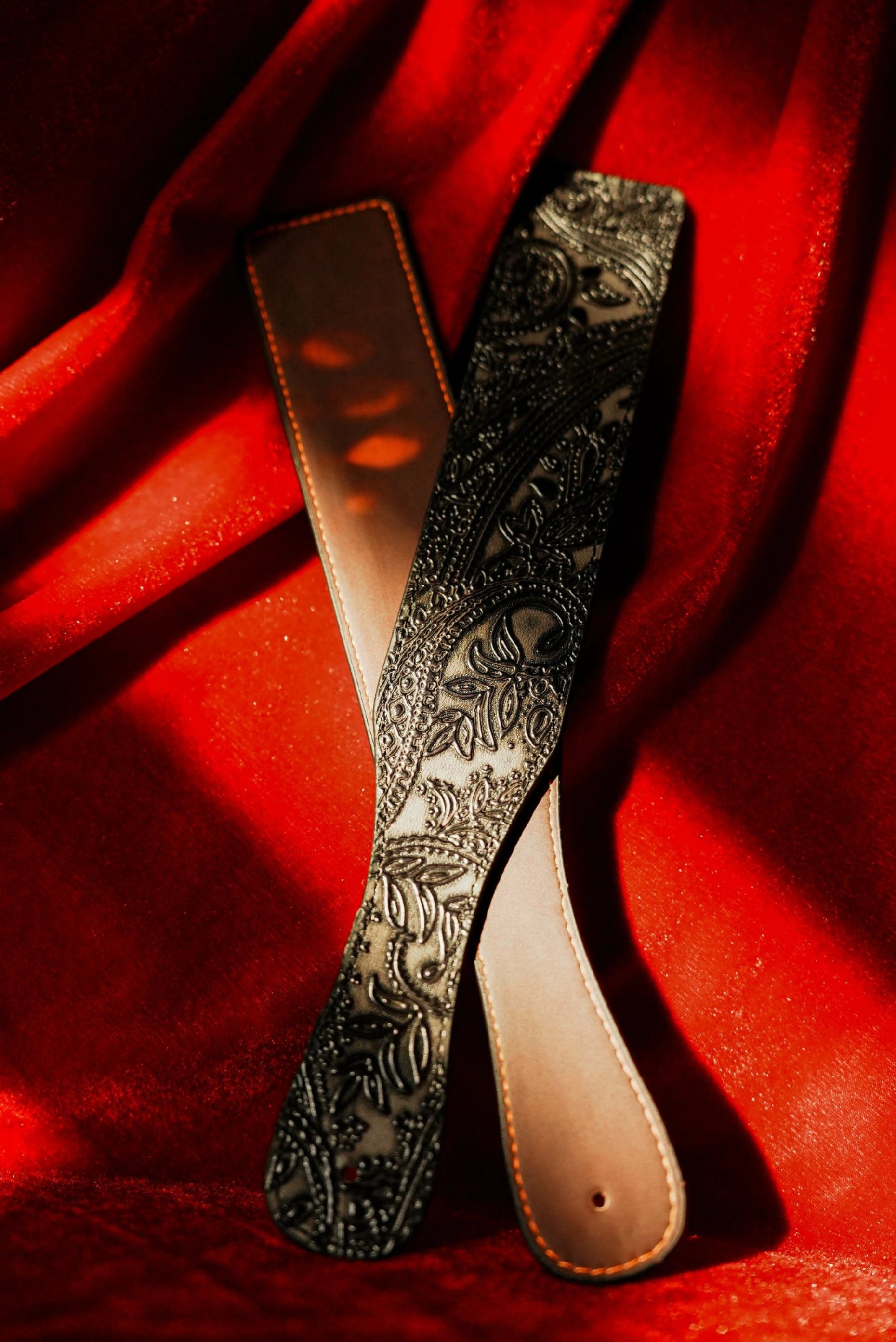 QIYE_Leather_Heat_Reactive_Spanking_Paddle_Red_banner: Two heat - reactive spanking paddles stacked on a red background, one side showing heat - reactive effect and the other side displaying exquisite patterns.