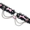 QIYE_Leather_Lilith_Collar_Choker_Heat_Reactive: A heat - reactive choker laid flat, featuring black lace, pink bows, metallic chains, and a pink bell. 